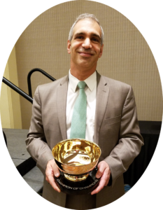 Yamil Kouri holding the 2019 Champion of Champions Award